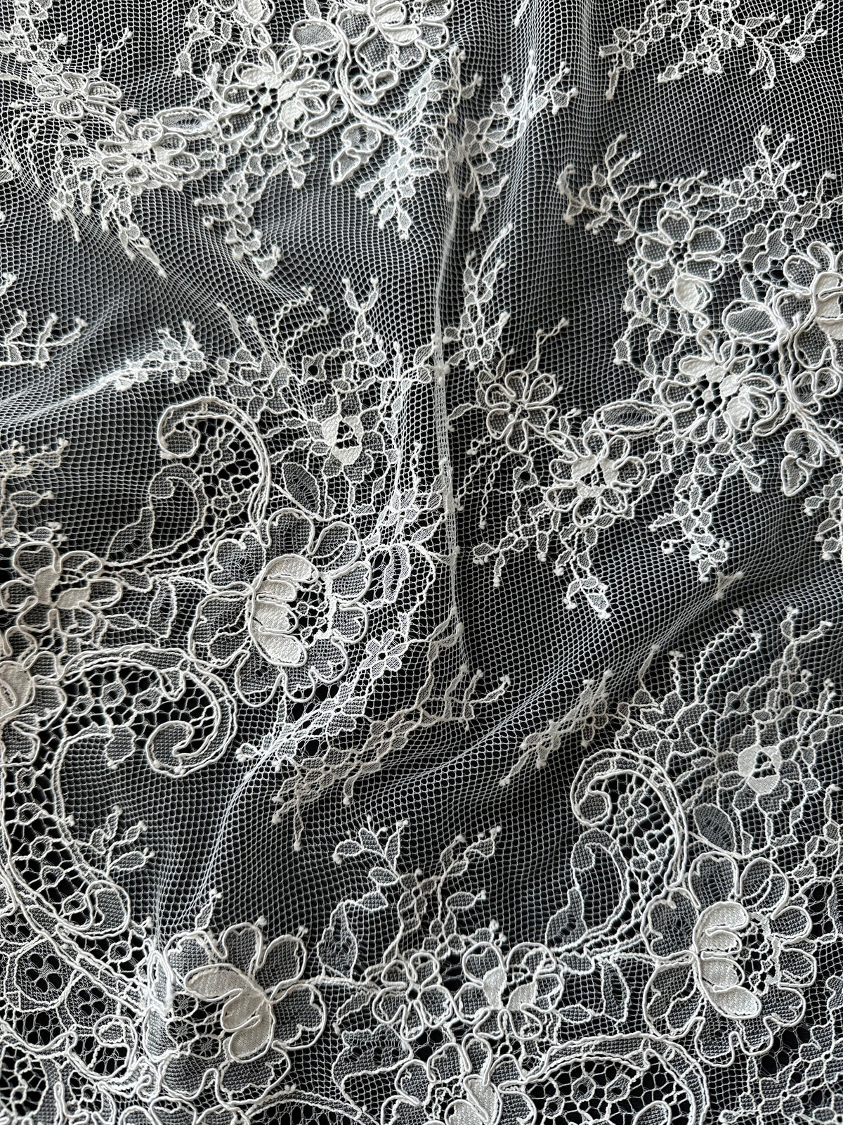 Close-up of intricate ivory lace fabric on a black background